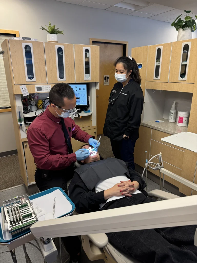 Dr. Cho treating a reclined patient with his assistant