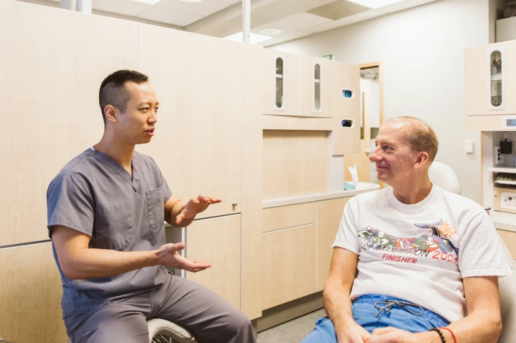 A smiling patient chatting with Dr. Cho in the dental chair