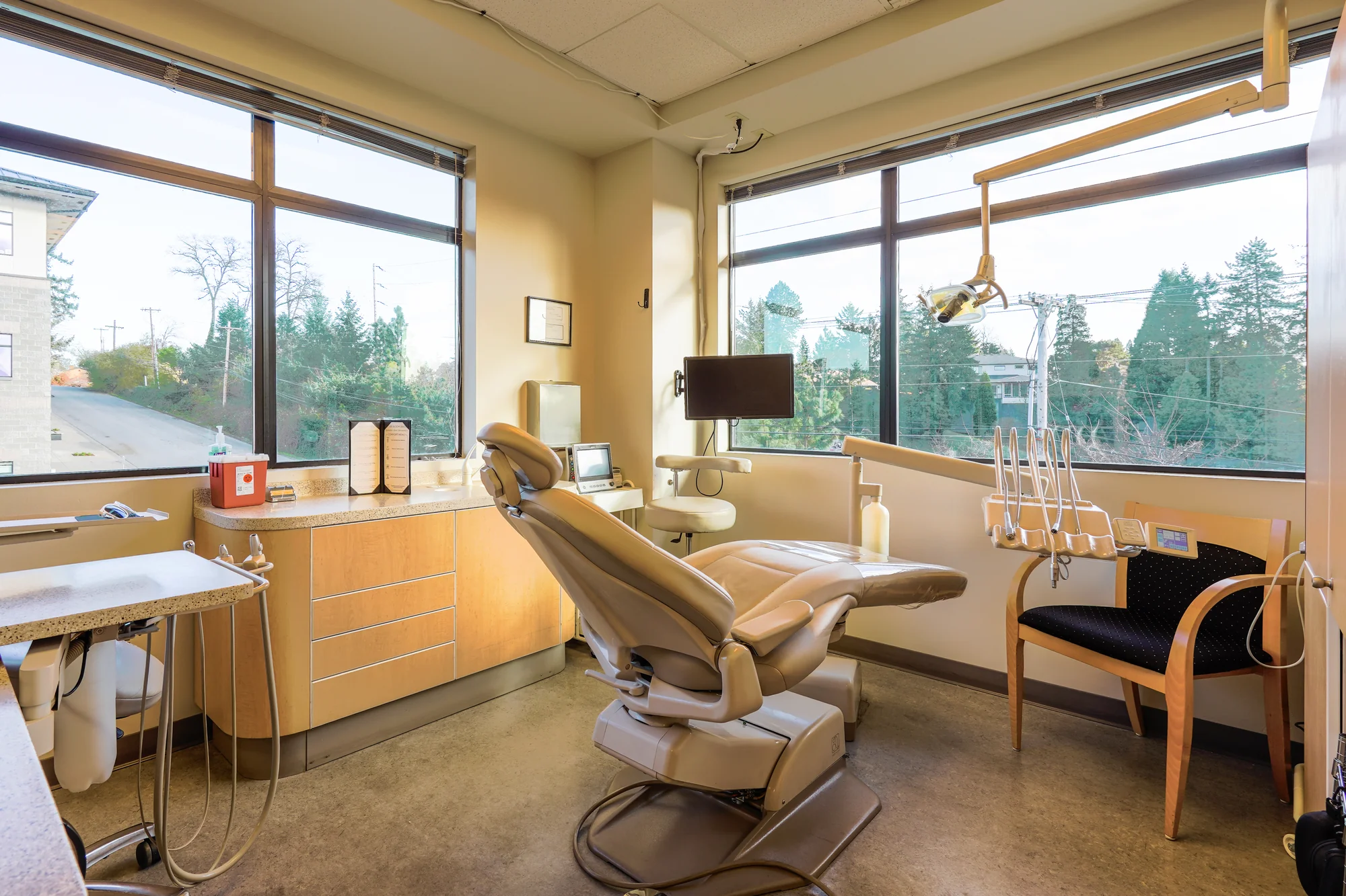 A bright treatment room with a window view and a ceiling TV